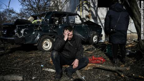 A man sits outside his destroyed building after bombings on the eastern Ukraine town of Chuguiv on February 24, 2022.